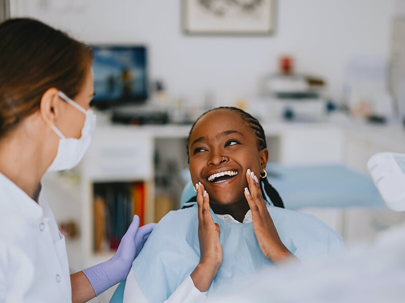 Patient in a dental clinic smiling at a professional wearing a mask.